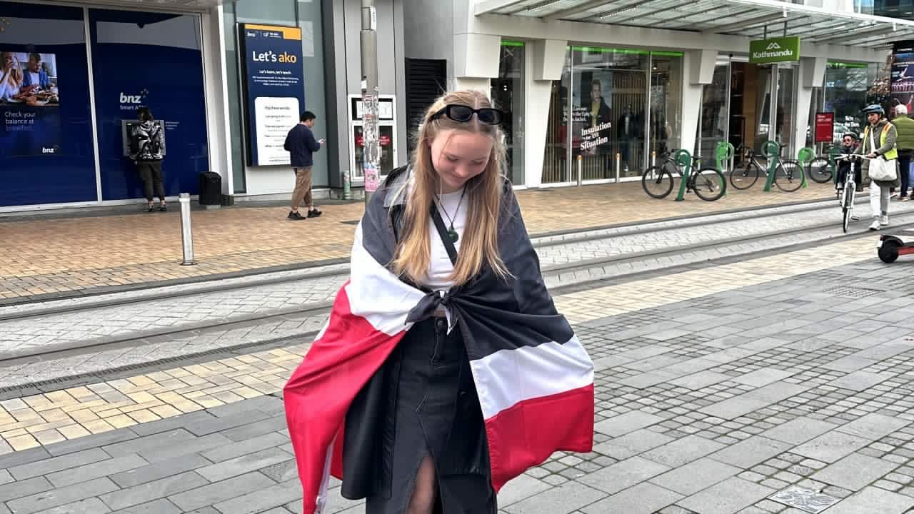 Emma Grace standing with a Māori flag around her