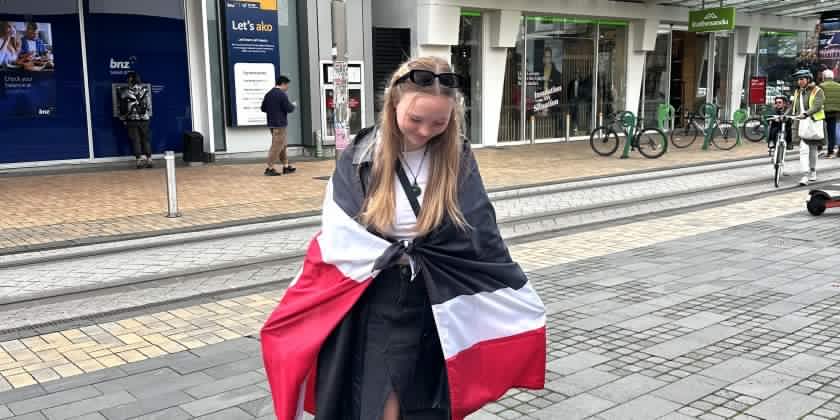 Emma Grace standing with a Māori flag around her