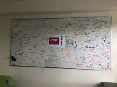 A white board with text around a NYDS poster