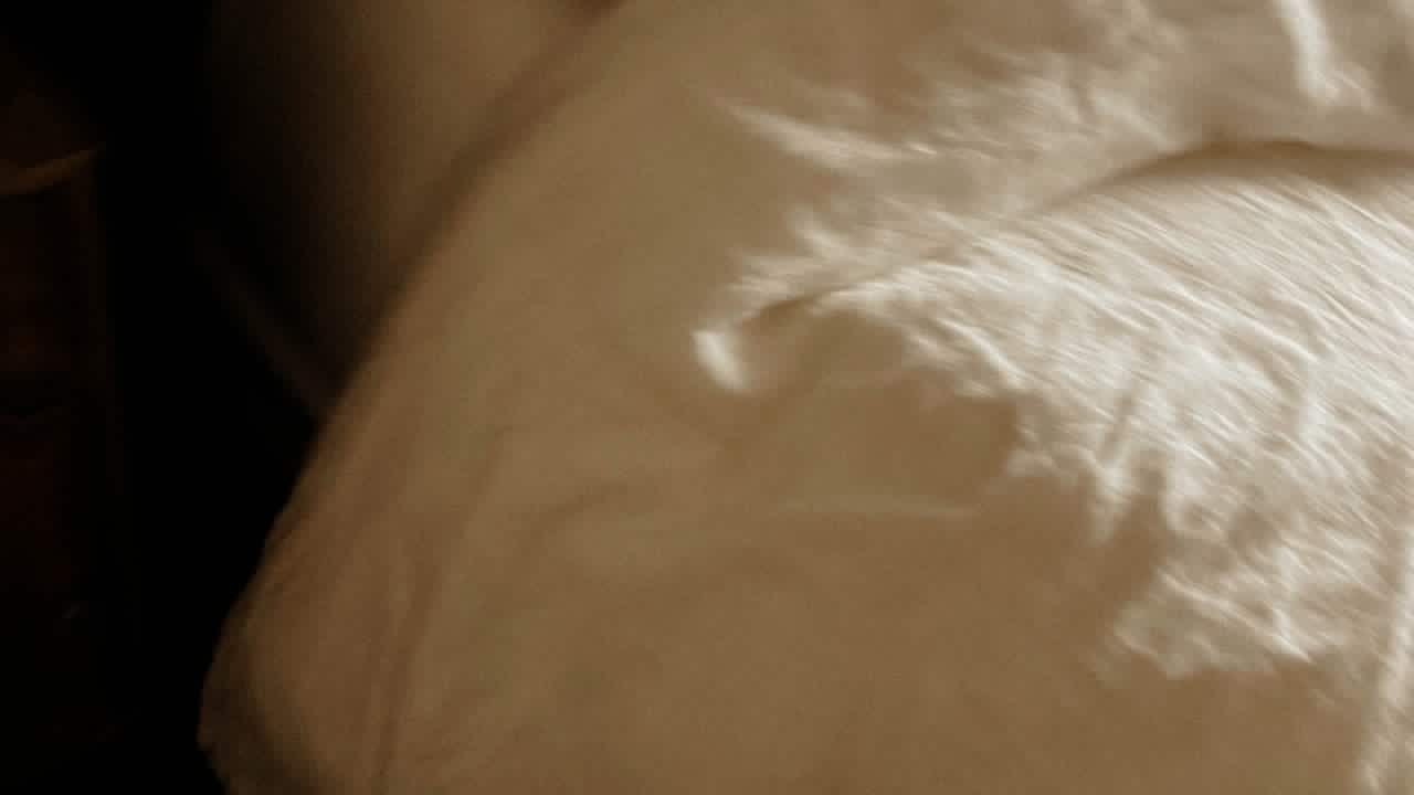 a bed with a plain white cover with natural dawn lighting